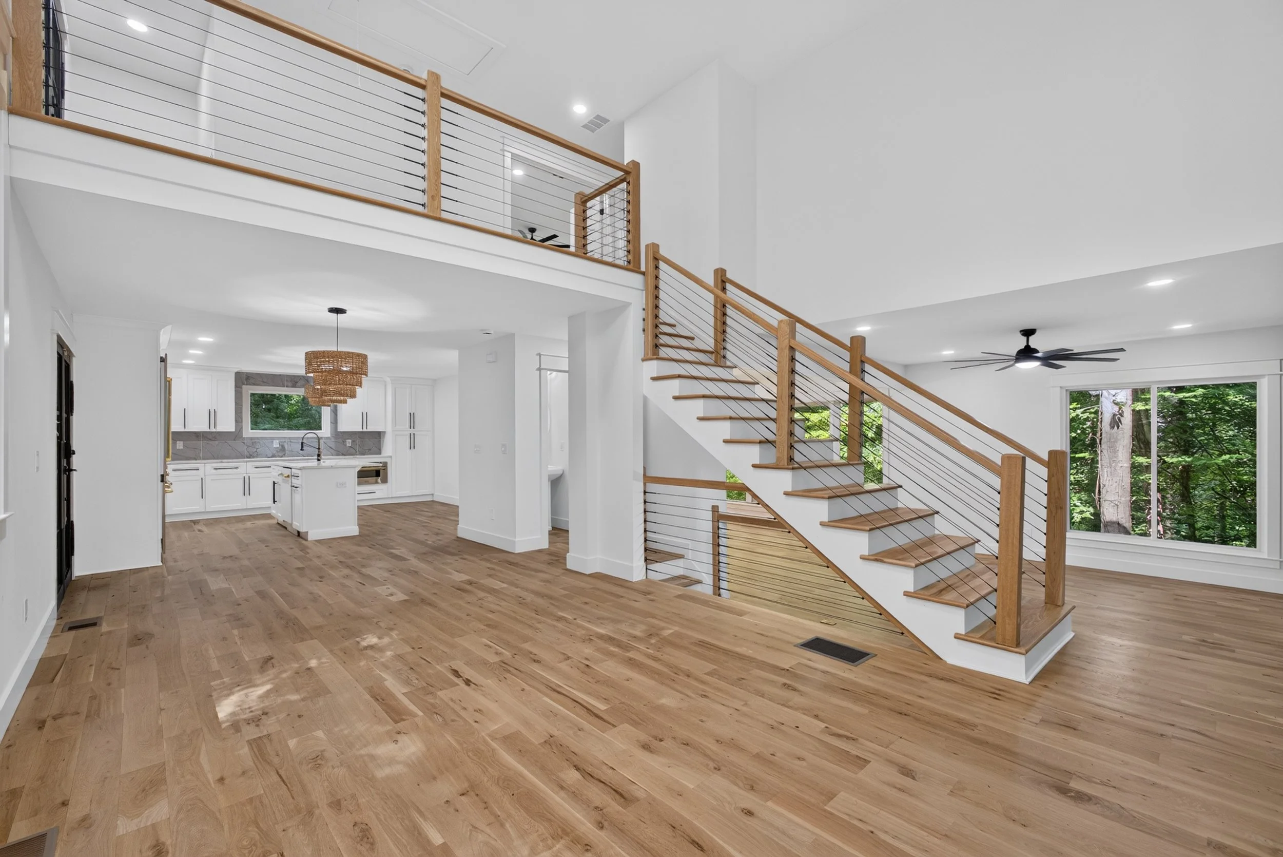 Modern three-story home interior with open loft, floating staircase, and wood-beam ceiling, real estate photography by Foundation Media Group in Gwinnett County, Georgia