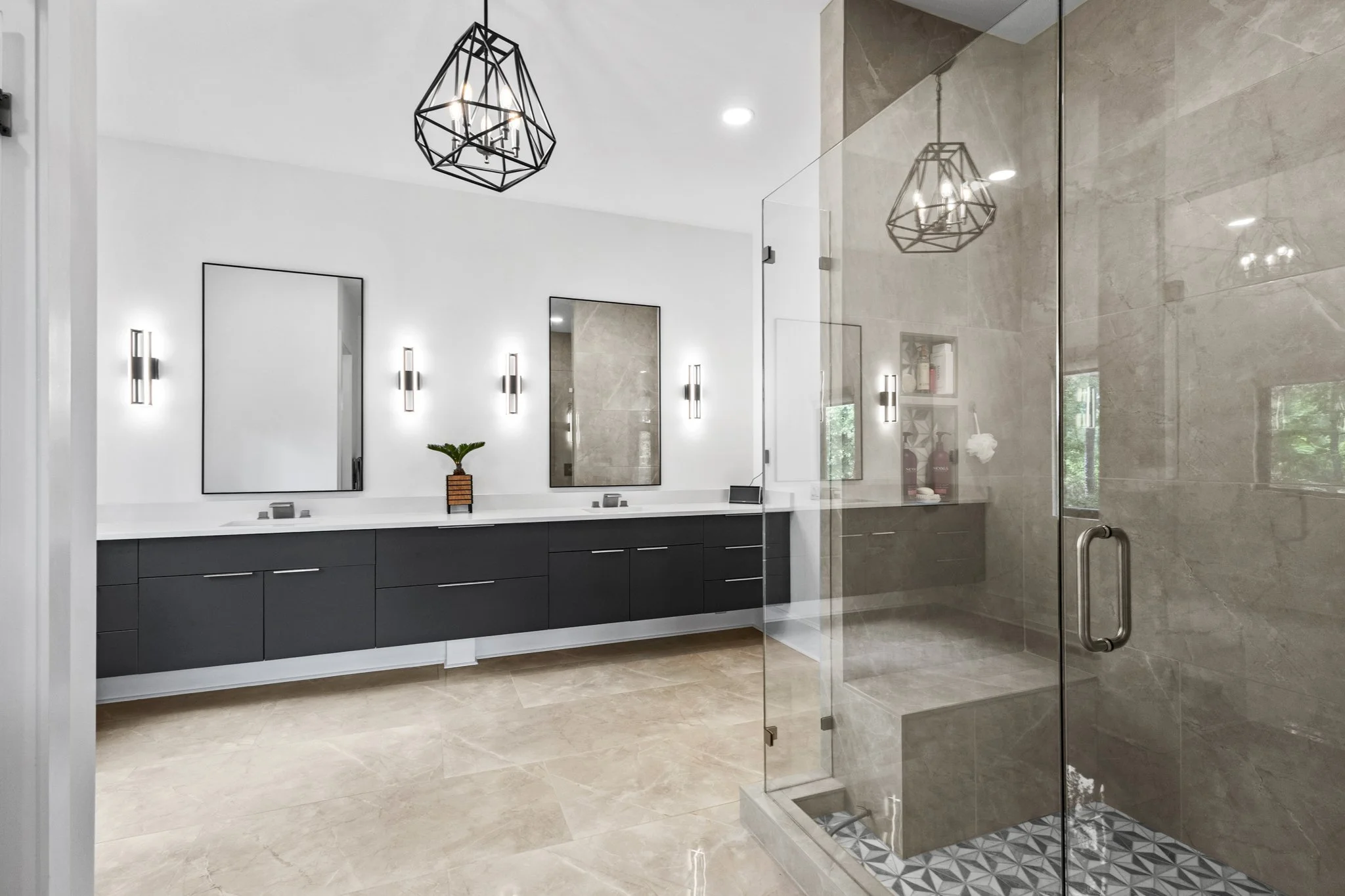 Modern bathroom with double mirrors, black vanity, geometric pendant lights, beige tiled floor and shower with glass enclosure.