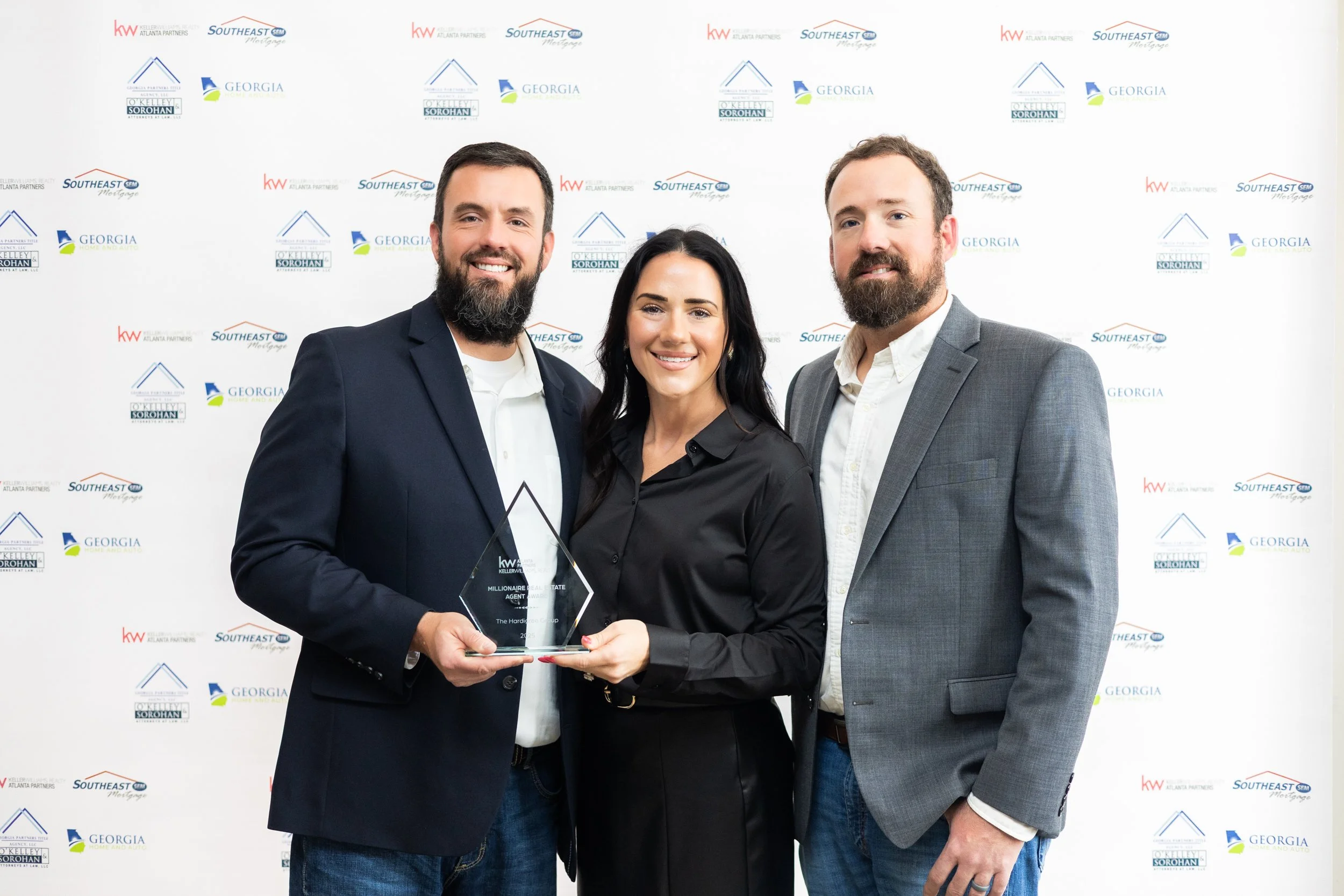 Three real estate professionals posing with an award at a Keller Williams Southeast Georgia event, corporate event photography by Foundation Media Group