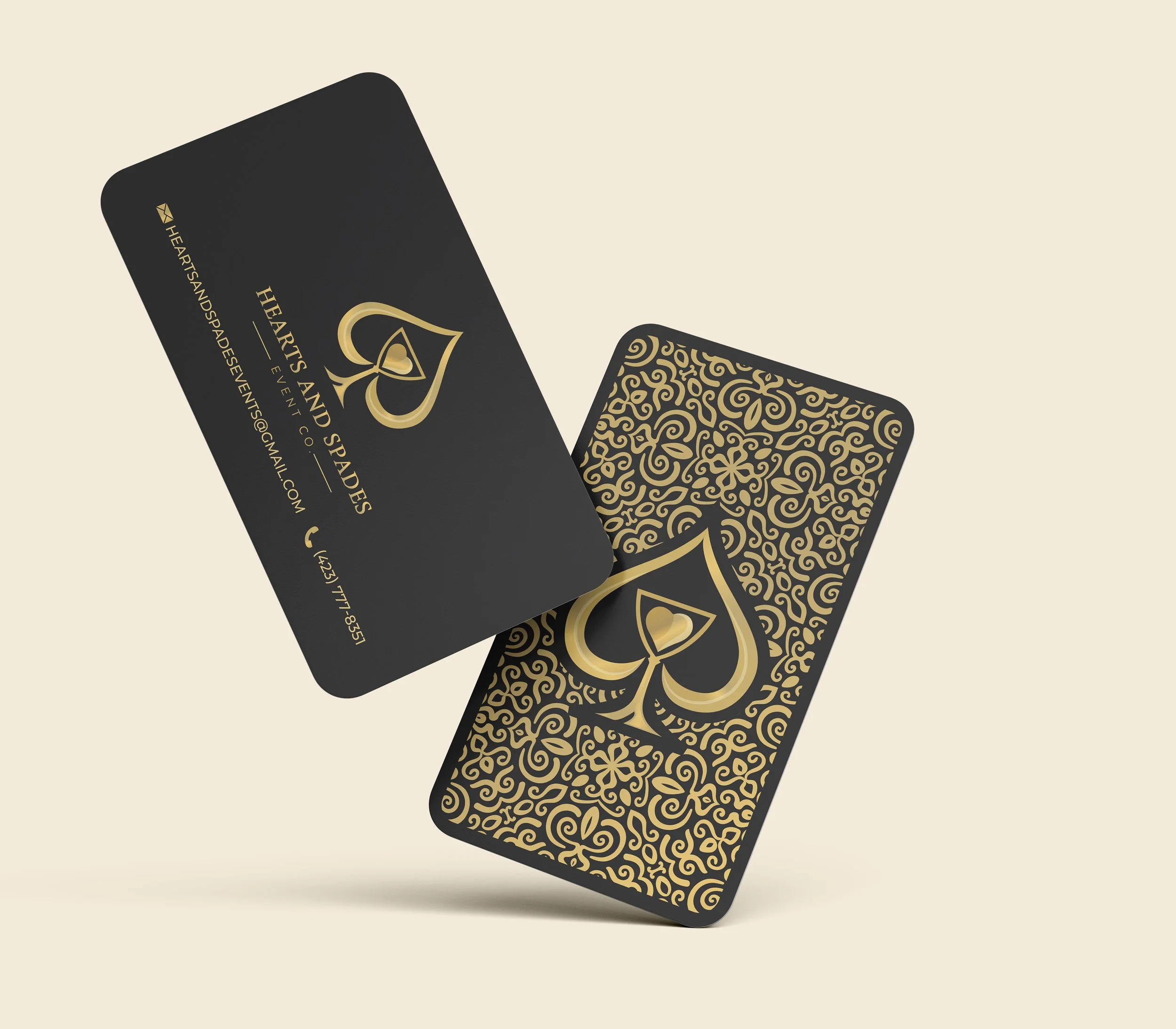 Two elegant business cards for Hearts and Spades event planning, featuring black and gold designs, with one card showing the front and the other the back with intricate patterns.
