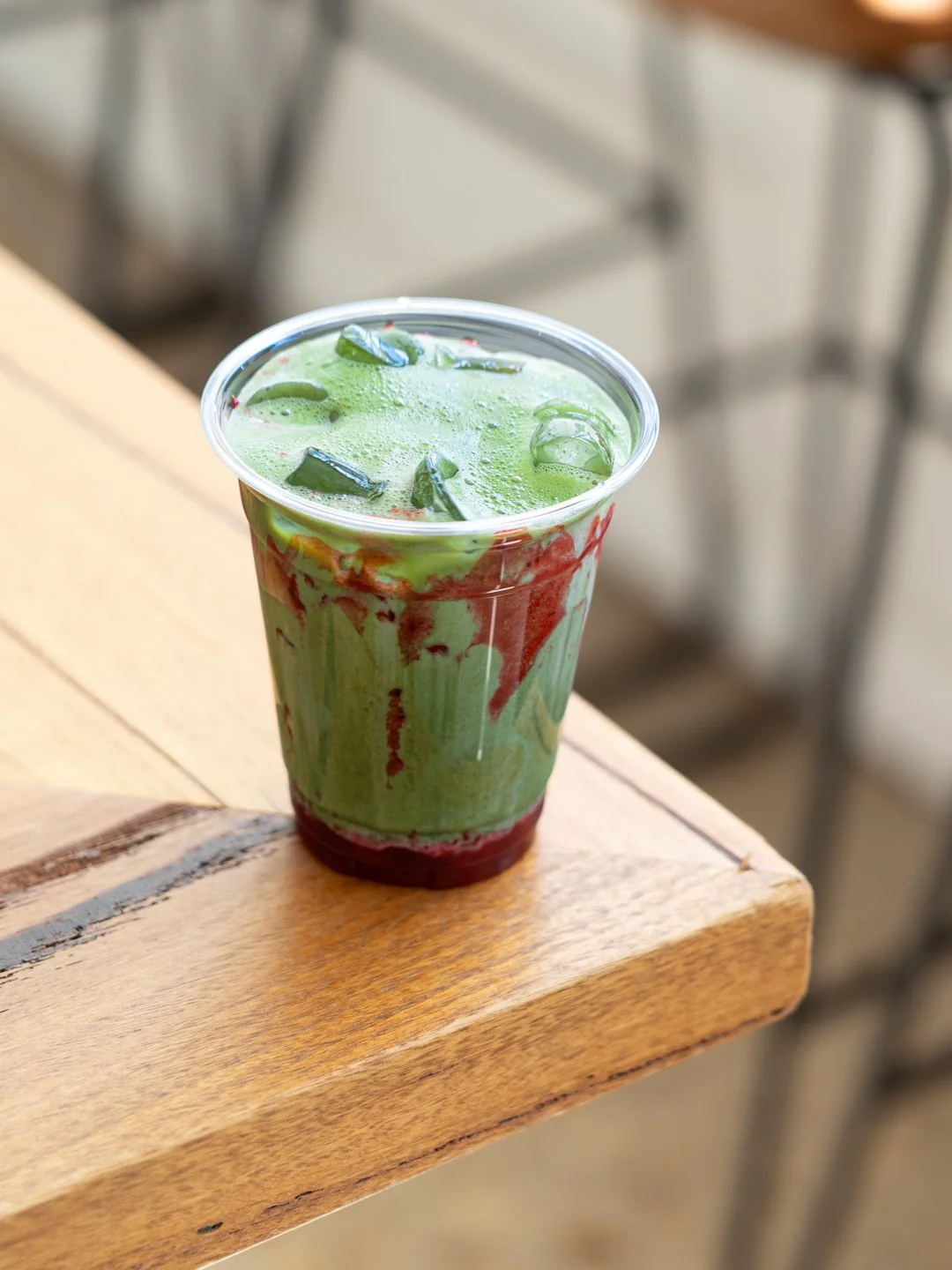 Cold matcha beverage in a plastic cup, filled with ice and a green liquid.
