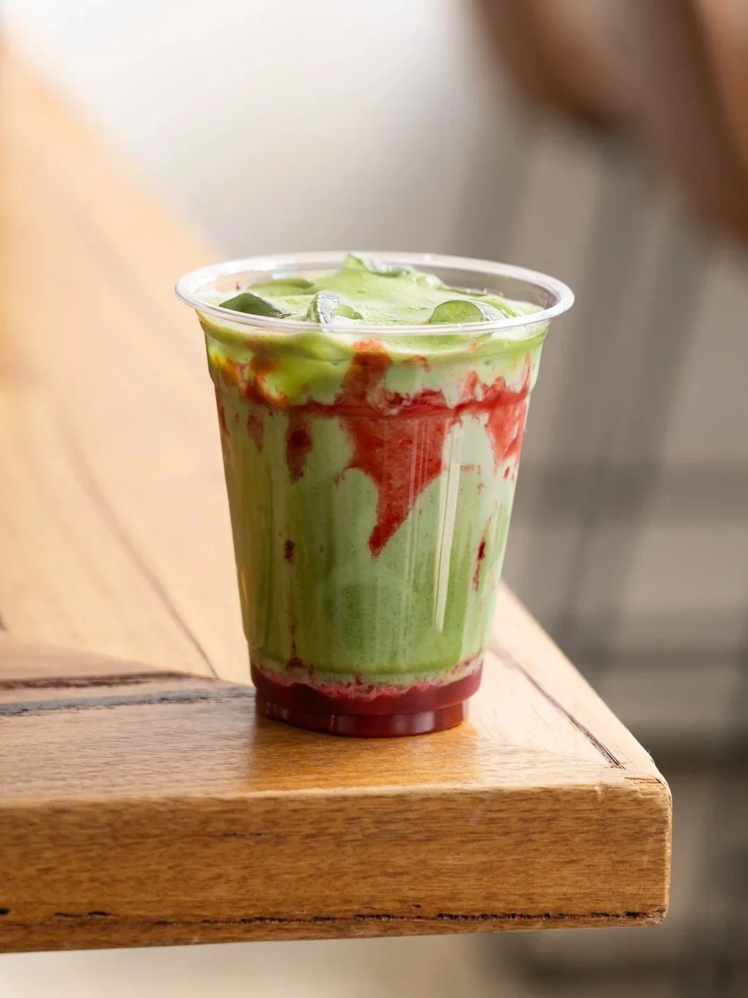 Iced matcha drink in takeaway cup sitting on table