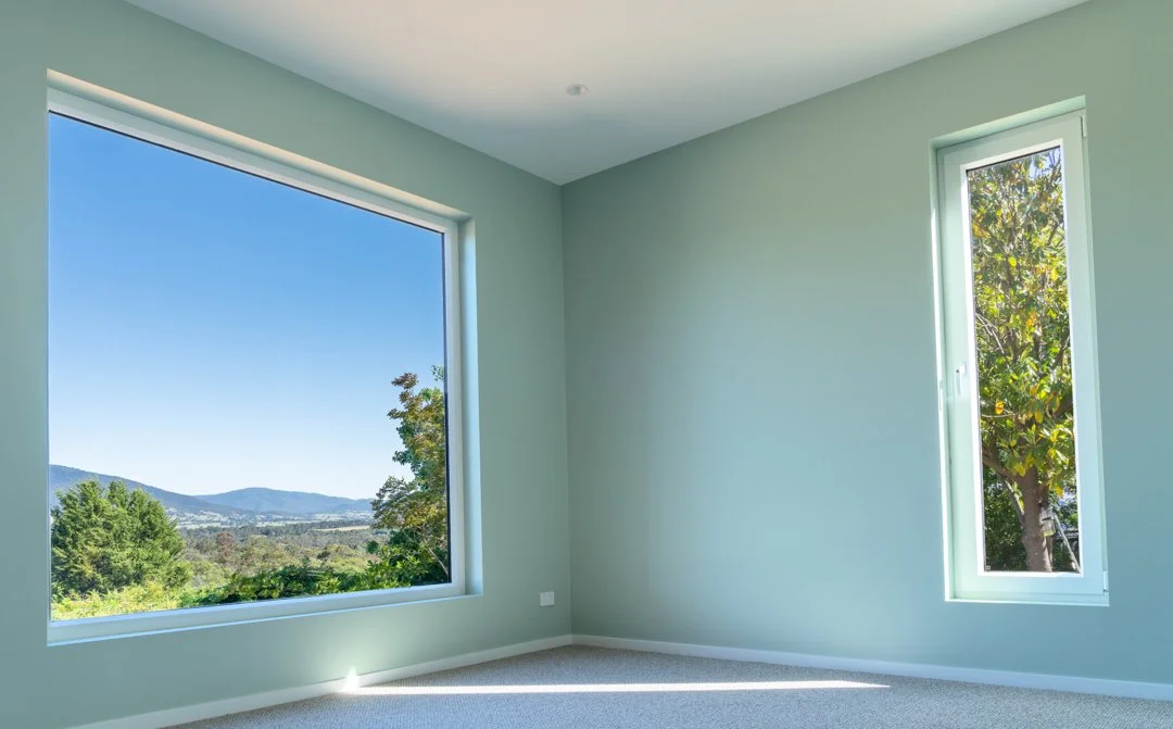 Room with green walls and 2 windows looking out to garden