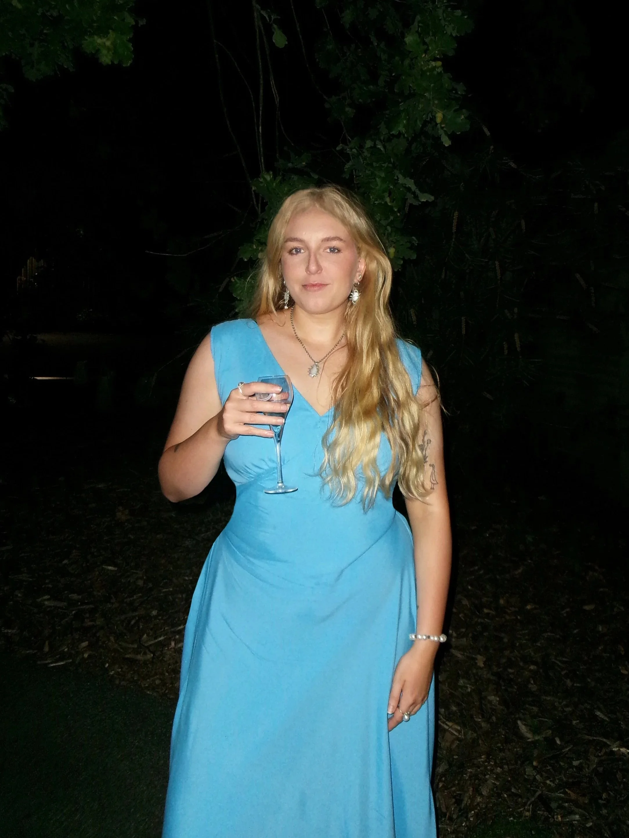 woman wearing blue dress holding glass of wine