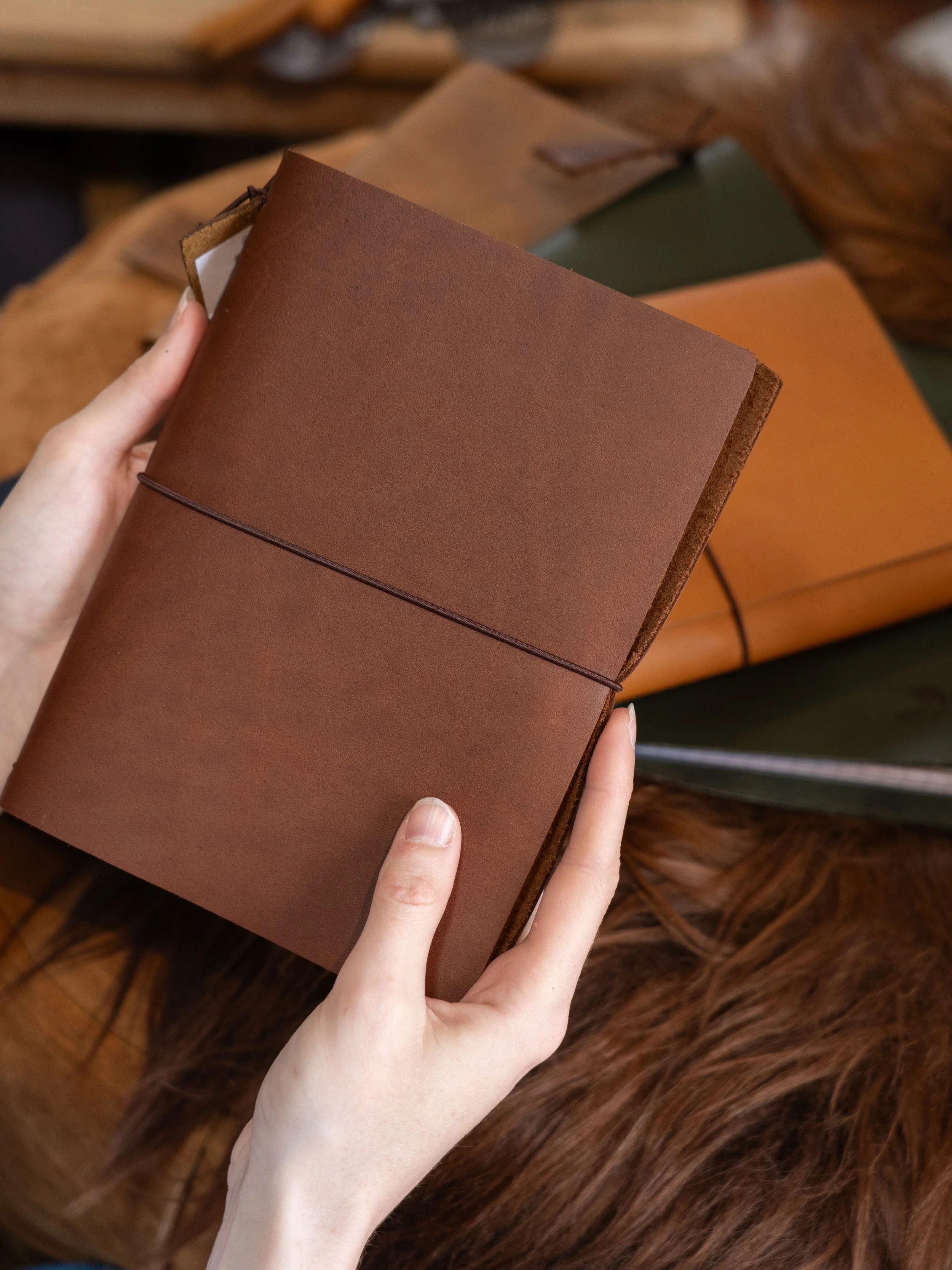 Hand holding a brown leather journal