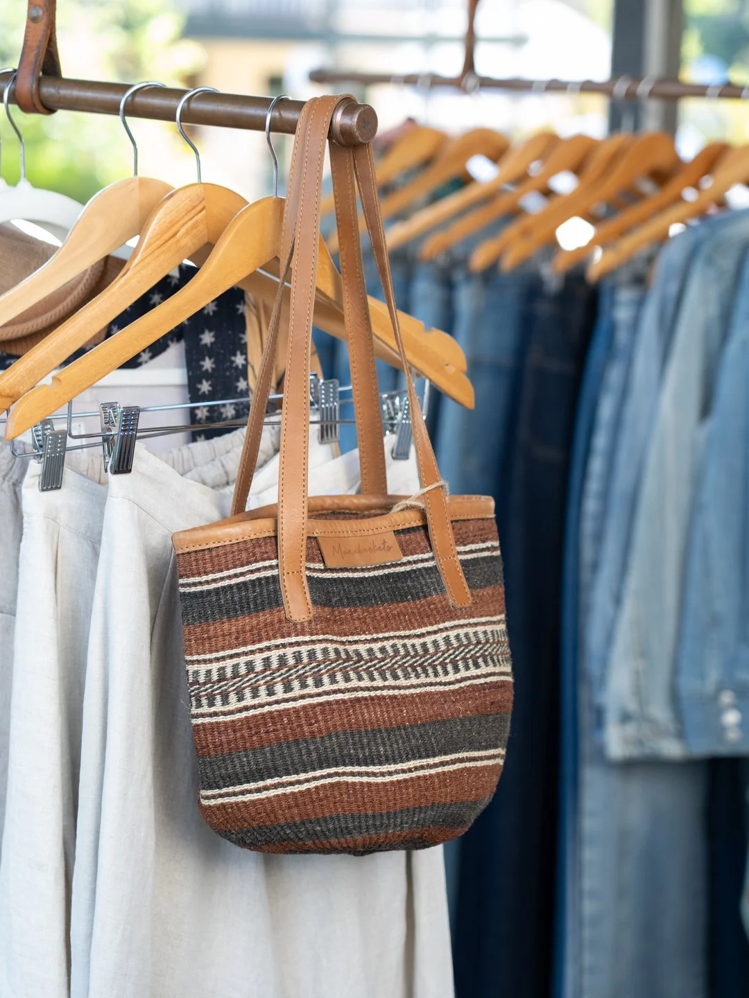 Handmade bag sitting on end of clothing rack