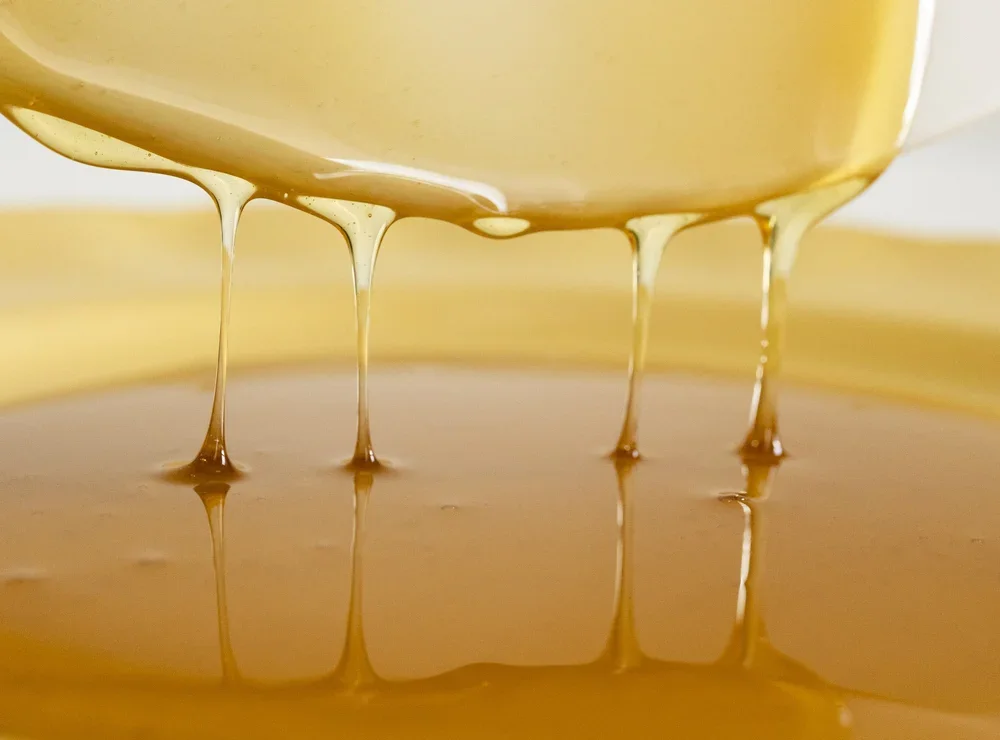 Close-up of honey dripping from a knife into a bowl.