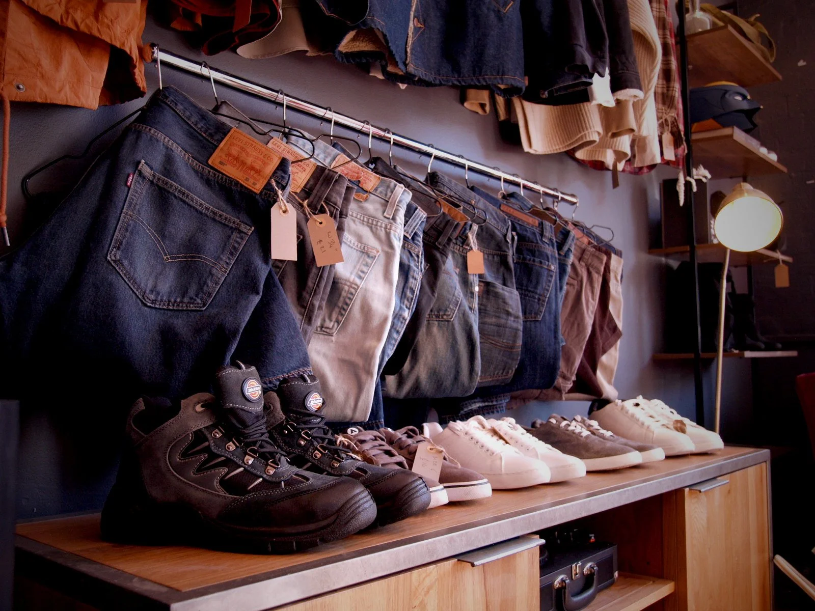 Collection of jeans and sneakers displayed on a wooden table at a clothing store.