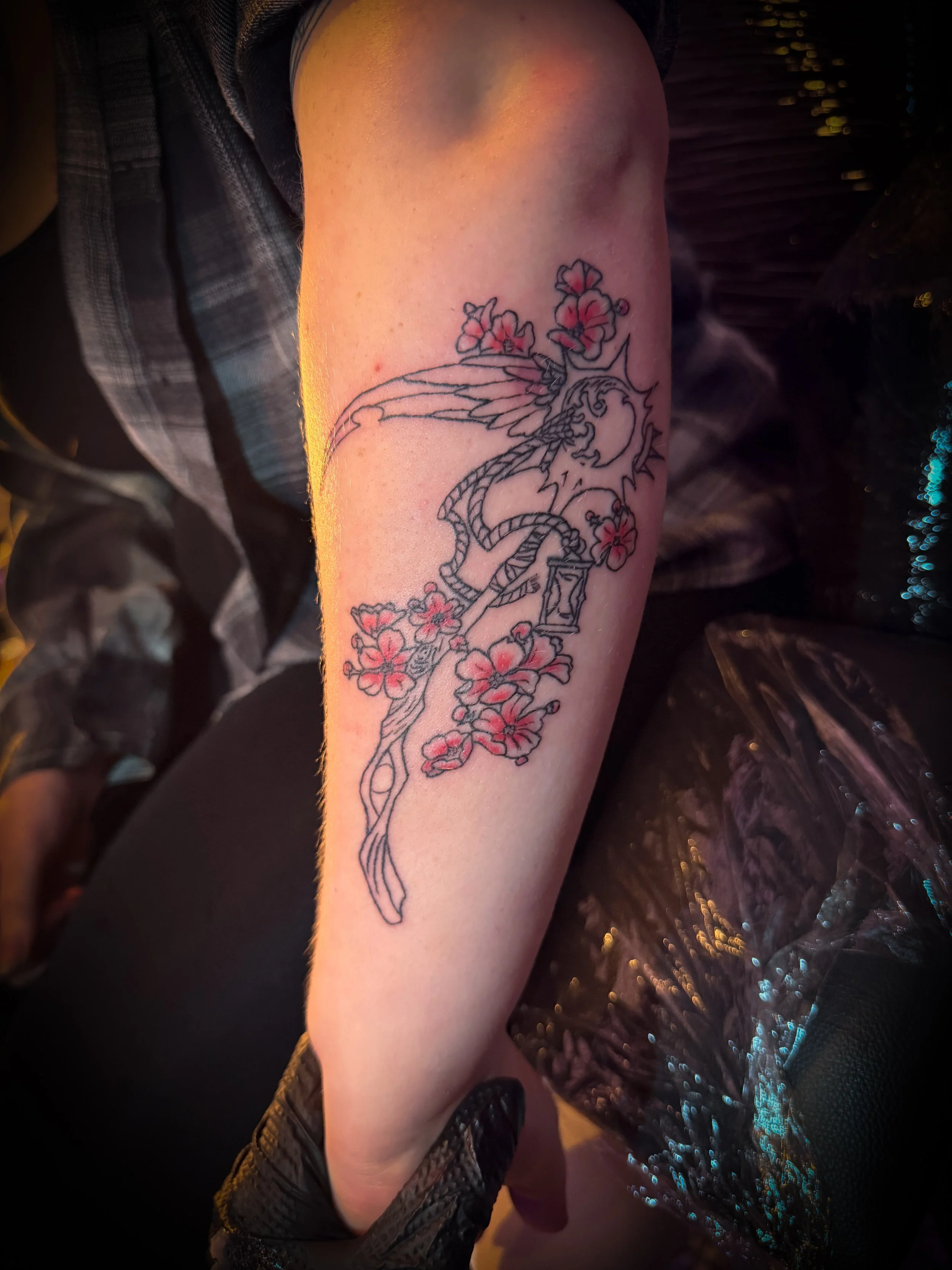 Tattoo of a flamingo with pink flowers on the arm.