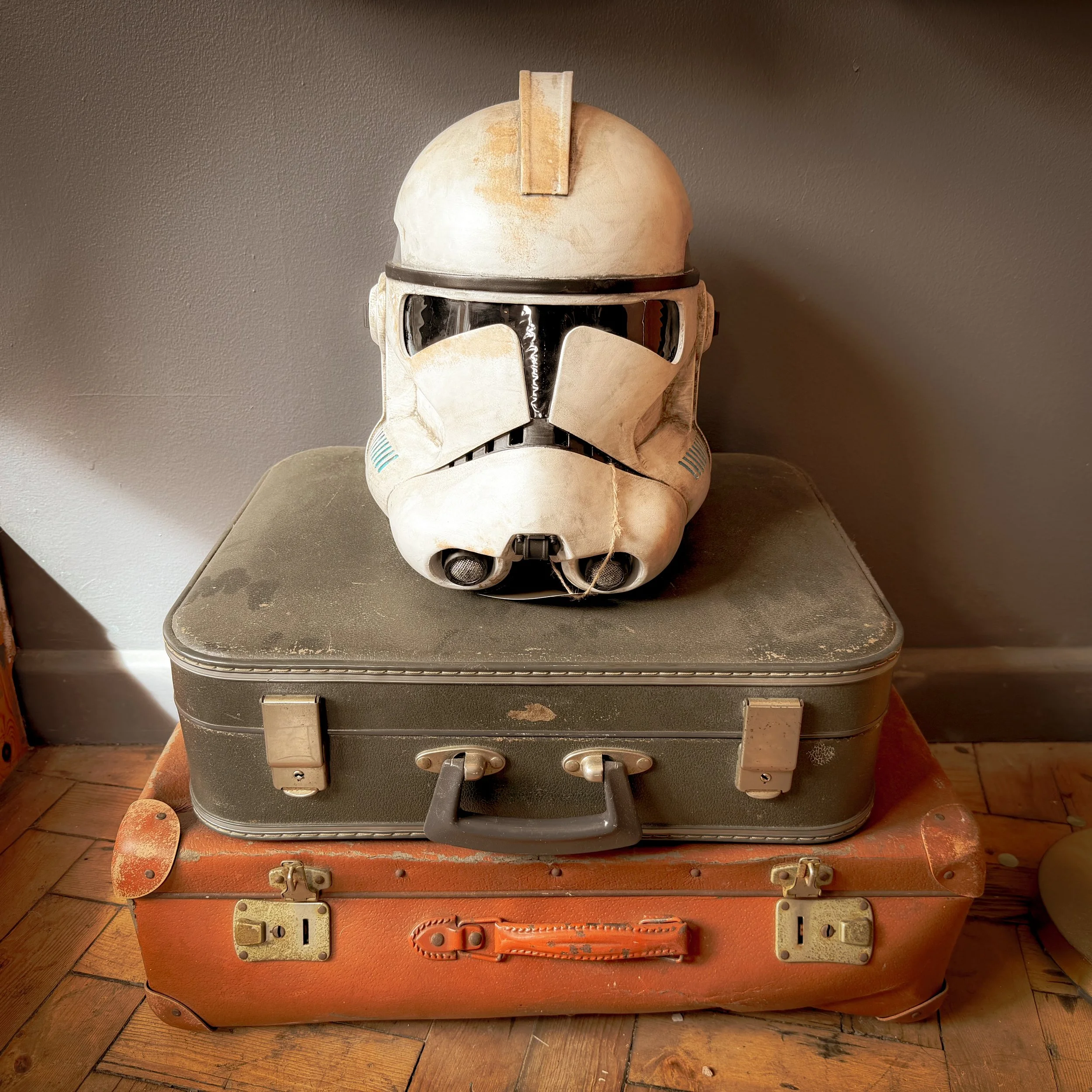 Star Wars Stormtrooper helmet placed on stacked vintage suitcases inside a room.