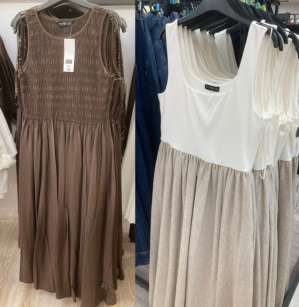 One brown and one white and tan dress, both sleeveless, hanging on a shop rail.