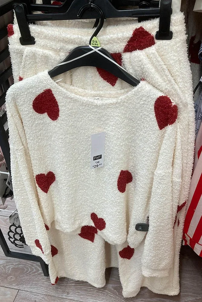 A pyjama top and trousers set in fuzzy white fleece with large red hearts.