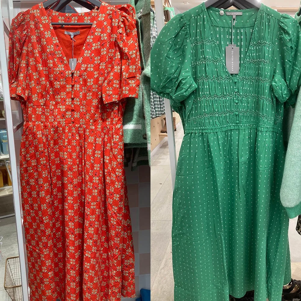 Two dresses. On the left is an orange one with a strawberry pattern, on the right is a green one with little white dots.