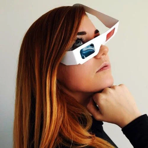 Woman with long red hair wearing 3D glasses.