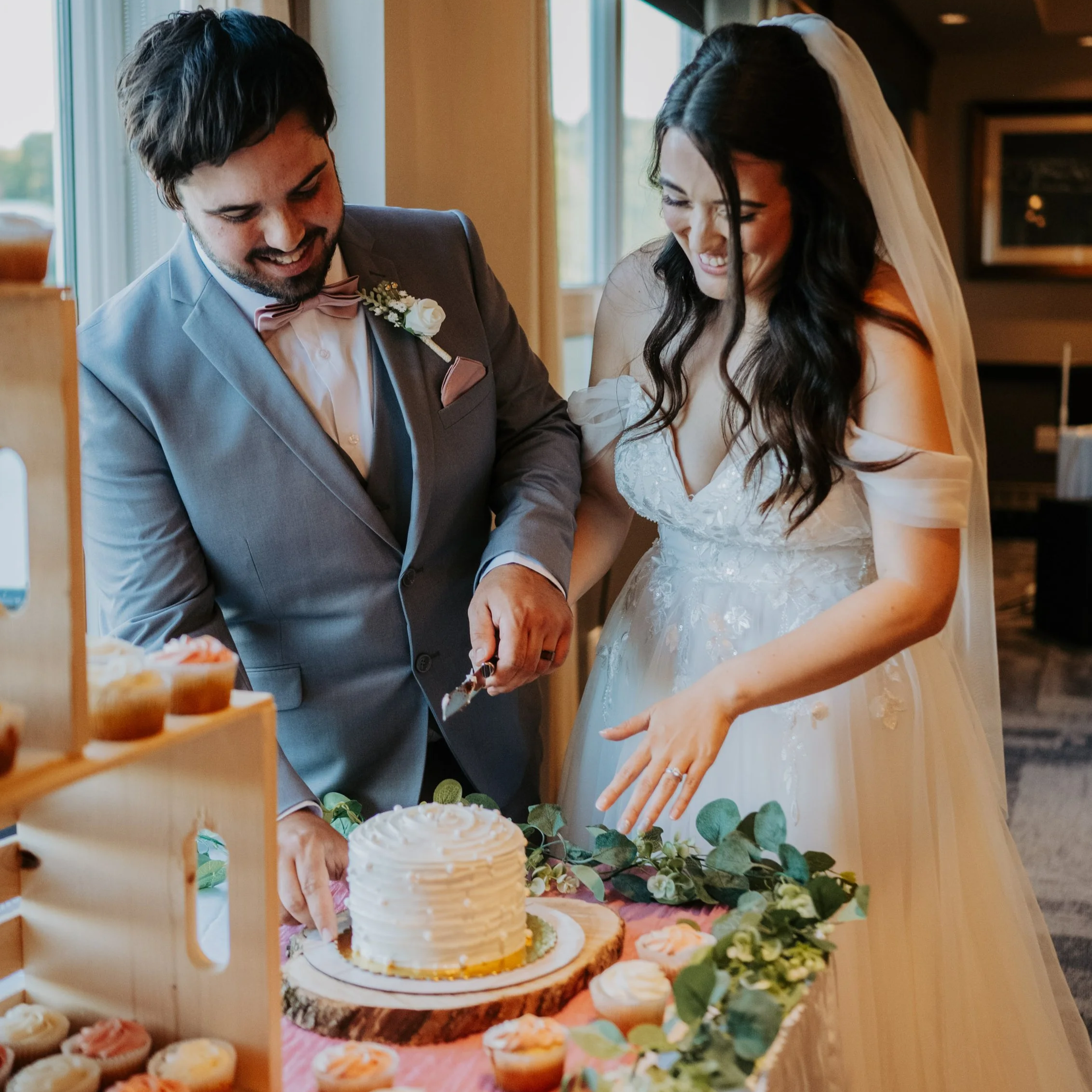 A bride and groom cutting a wedding cake at their reception, held in one of the ballrooms at Best Western Plus Chocolate Lake.