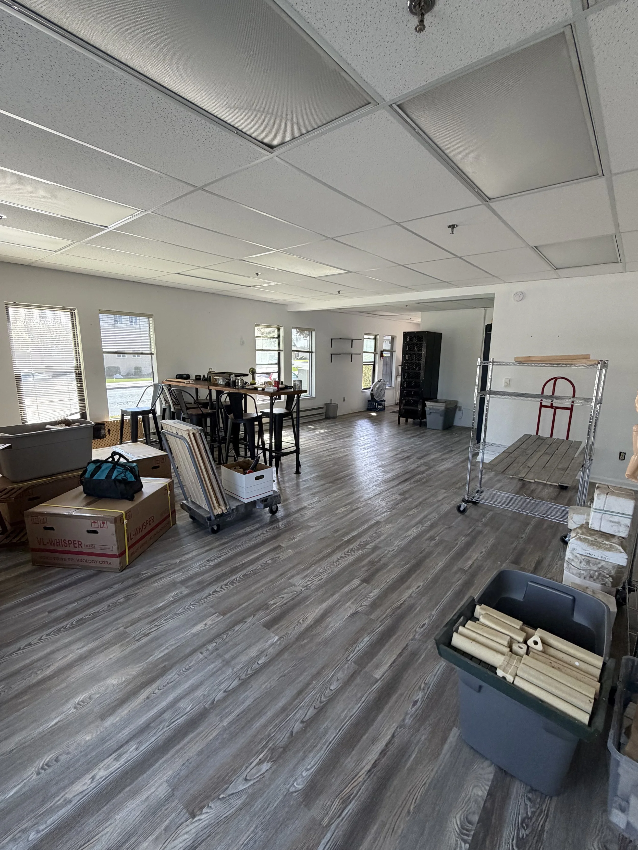 Empty room under renovation with boxes, furniture, and construction materials scattered on the floor.