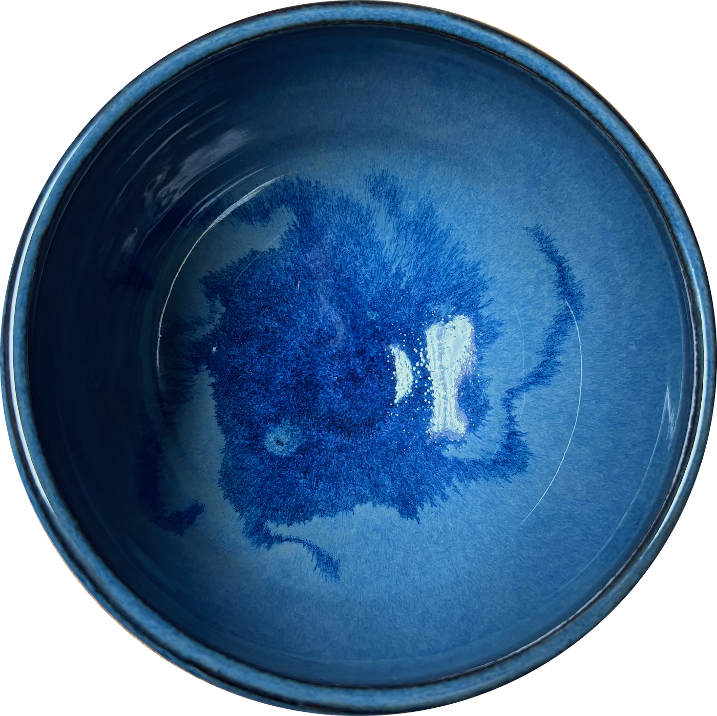 Close-up of a blue ceramic cup with a dark blue interior and a speckled blue pattern at the bottom.