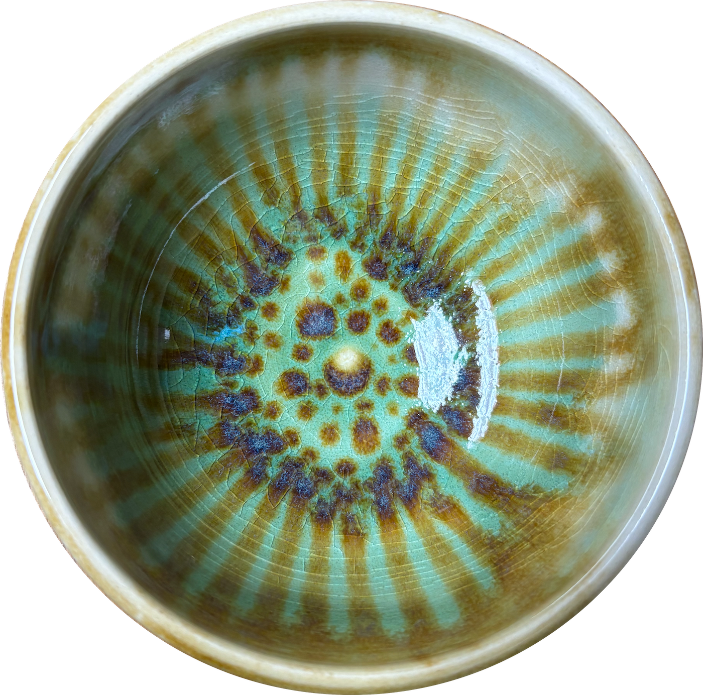 Close-up of a ceramic mug with a green, brown, and blue glaze pattern, showing a crackled surface and a textured interior.