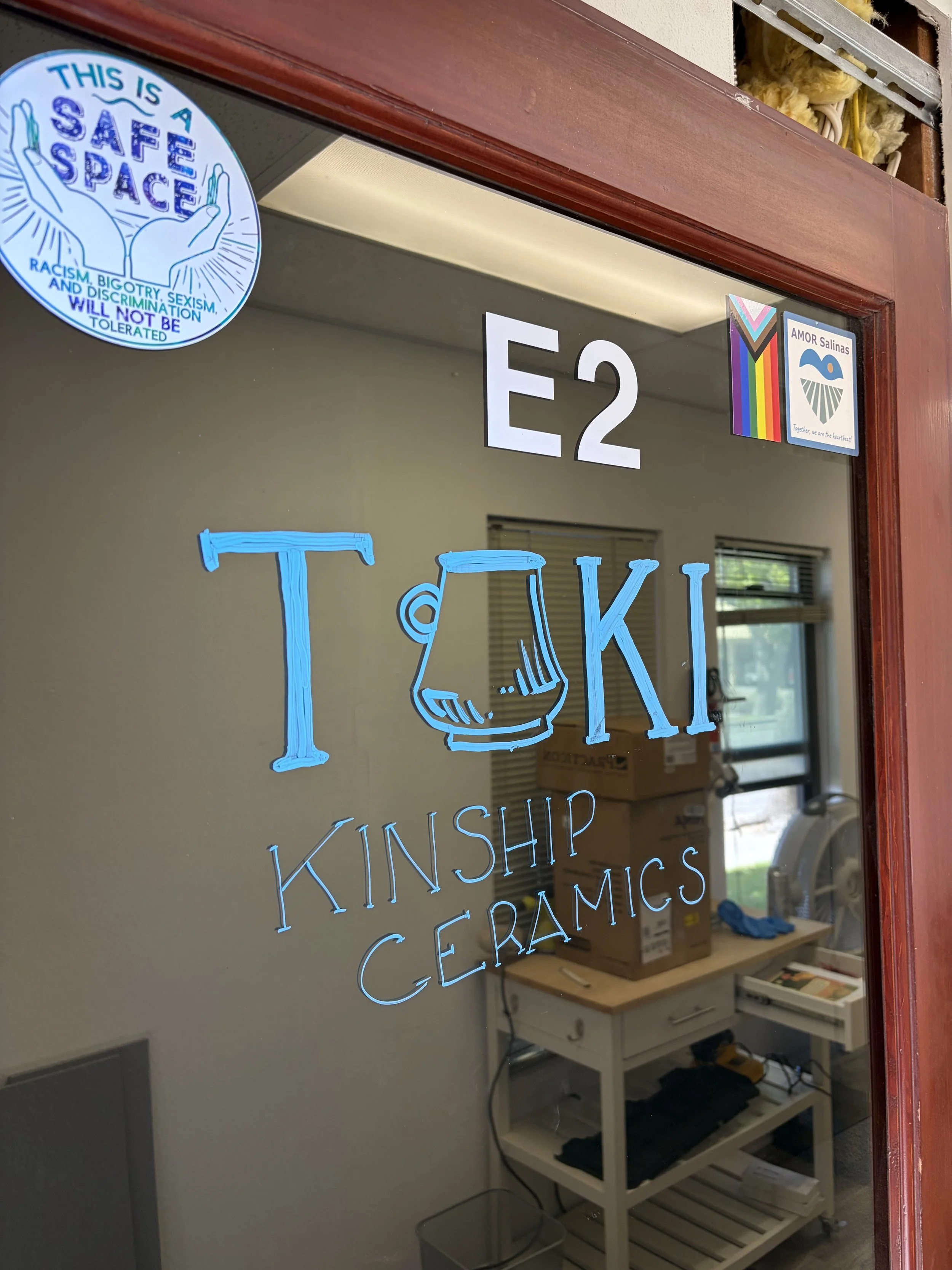 A door with a sign saying 'This is a safe space. Racism, bigotry, sexism, and discrimination will not be tolerated.' There are additional stickers, including a rainbow flag and one with the words 'Amor Salinas' with a heart design.
