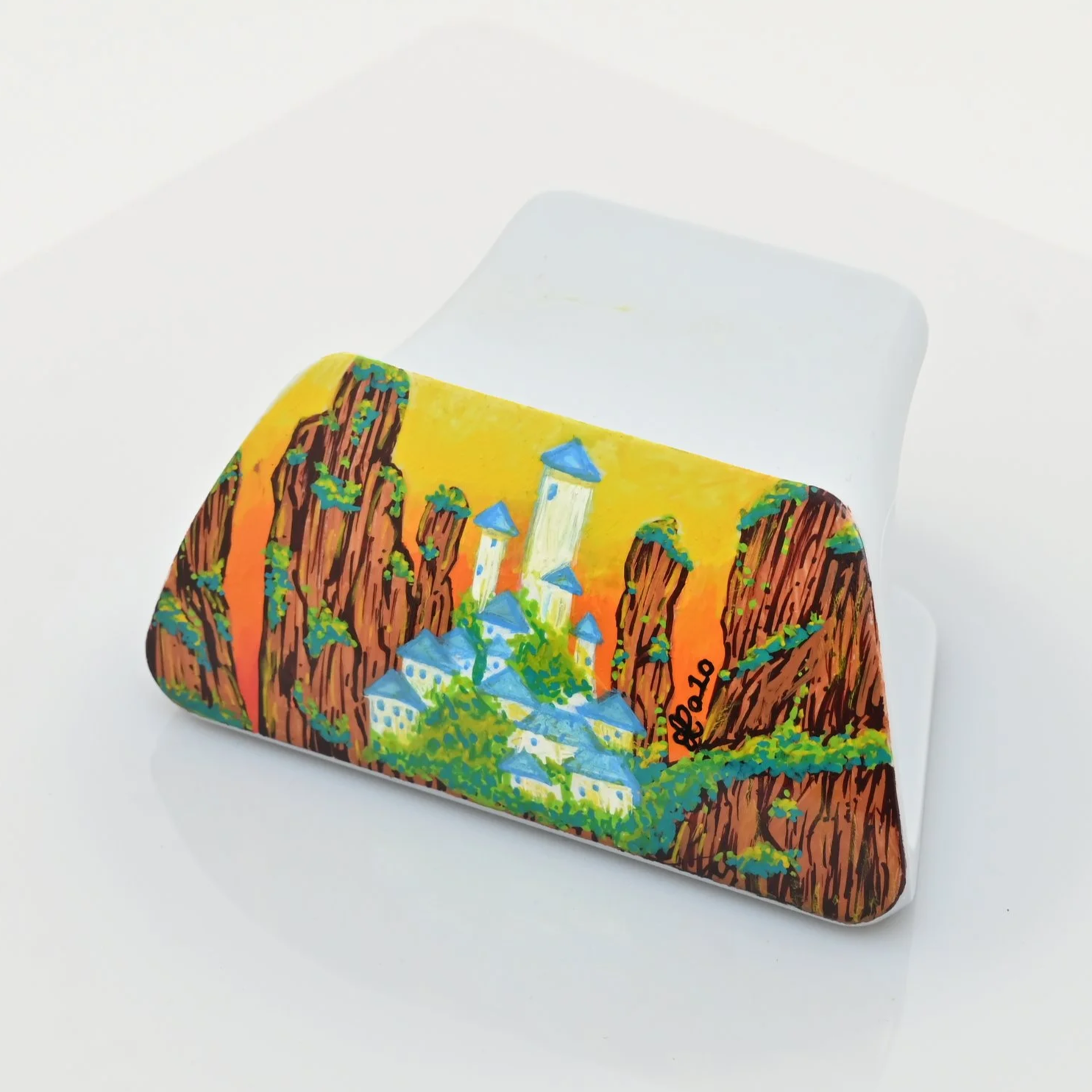 Colorful painted rocks with castle and mountain landscape on a white surface