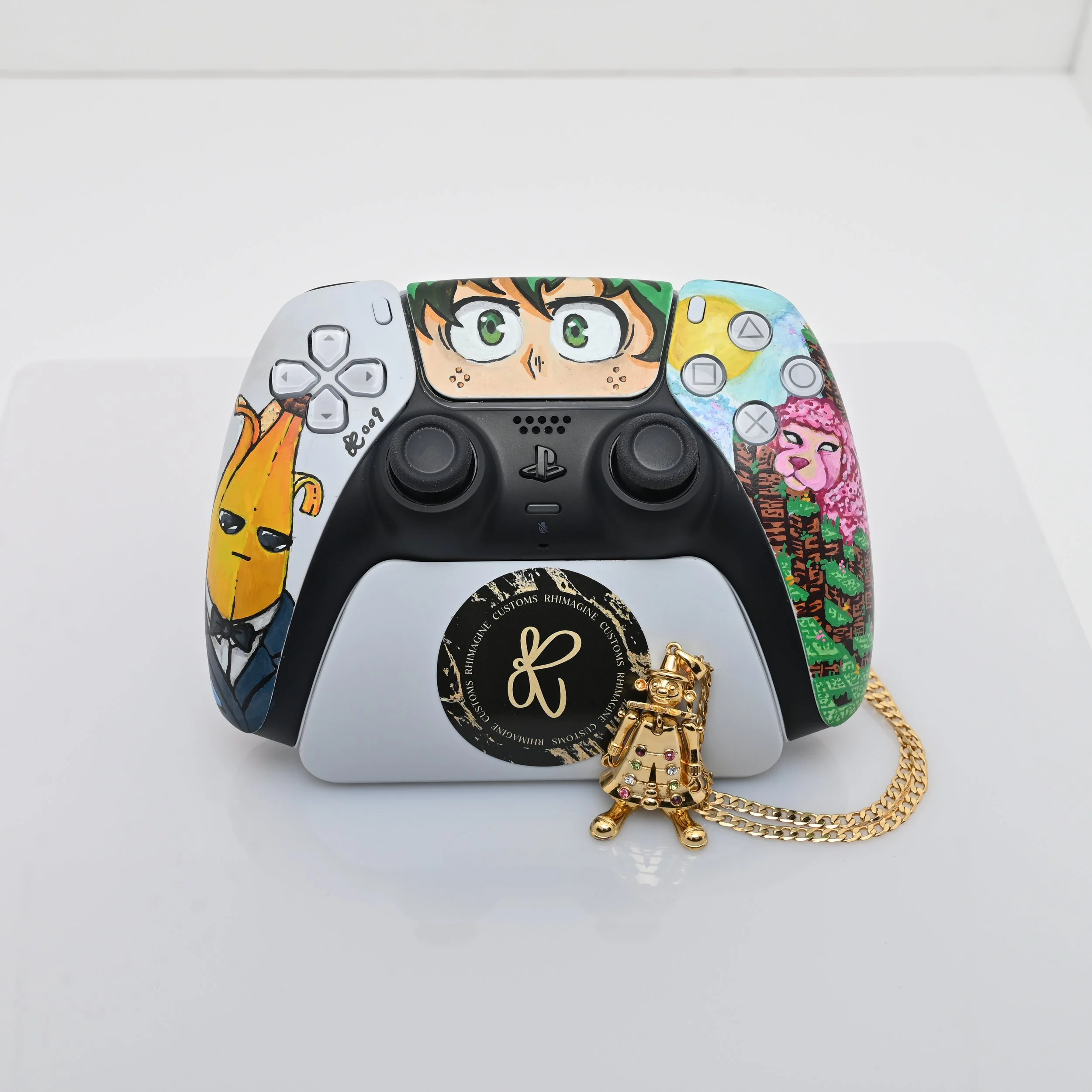 A custom-designed PlayStation 5 controller with colorful artwork, including deku mydoria, peely skin from fortnite and a minecraft sheep. In front of the controller, is a clown pendant gold necklace .