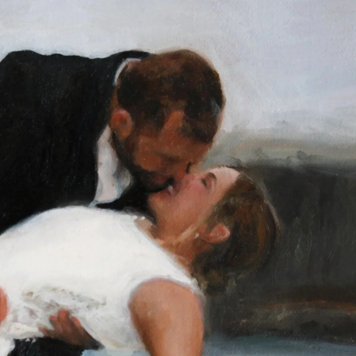 A man and woman sharing a kiss, with the man leaning over the woman who is lying down.