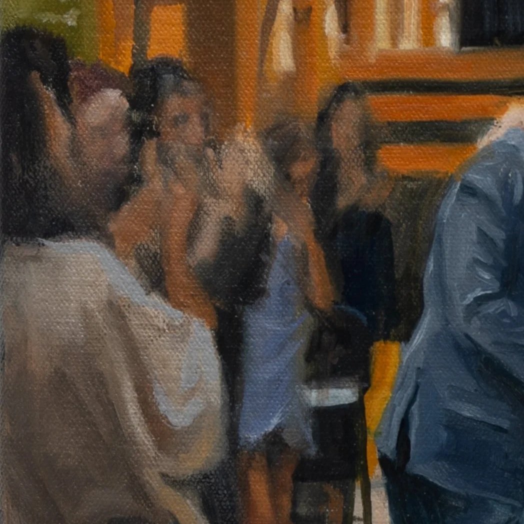 People sitting in a line on a bus or train, engaged in conversation or listening to someone speak.