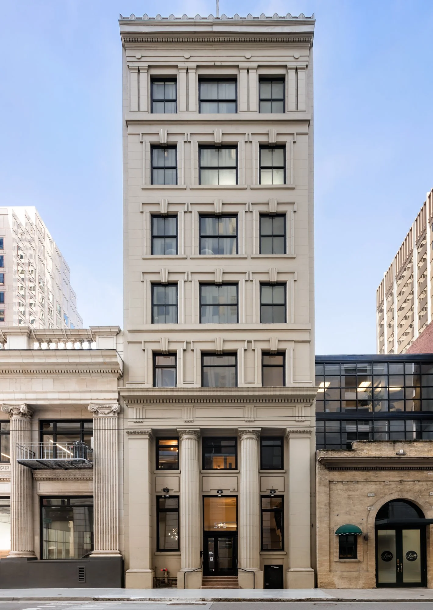 A tall, classical-style building with decorative columns and multiple floors, located on a city street.
