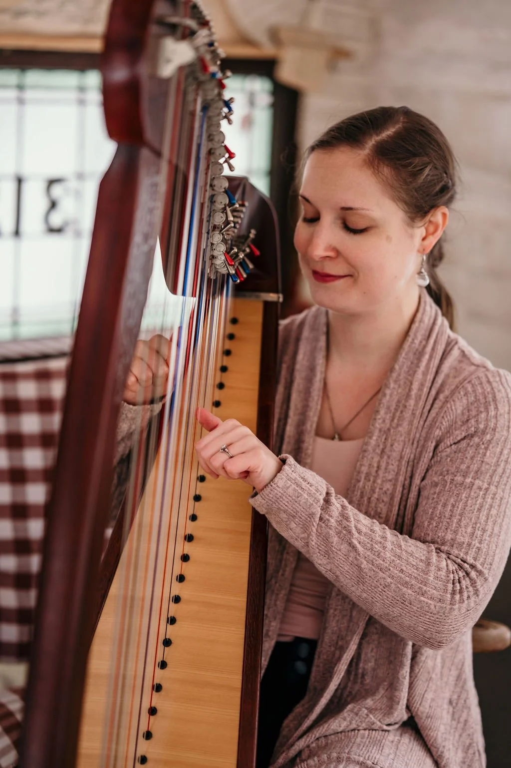 Une harpiste souriante joue de la harpe celtique avec sérénité.