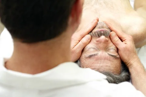 Une personne recevant un massage facial d'un professionnel dans un cabinet de soins.