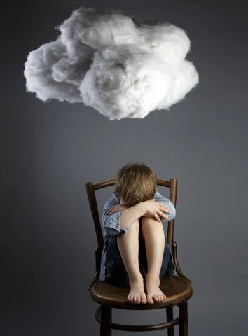 Un enfant assis sur une chaise, tête baissée, avant-bras sur les genoux, avec un nuage de vapeur au-dessus de sa tête, symbolisant la frustration ou la confusion.