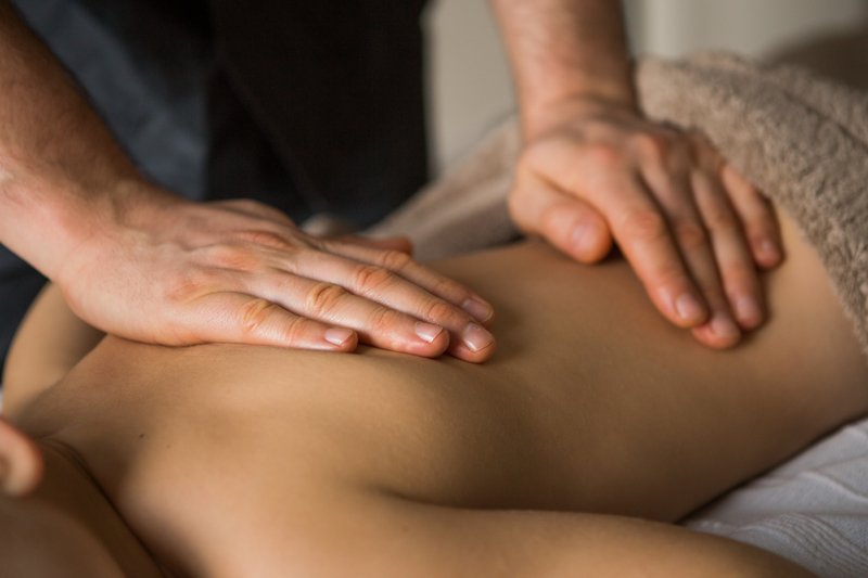 Une personne reçoit un massage du dos par un thérapeute.