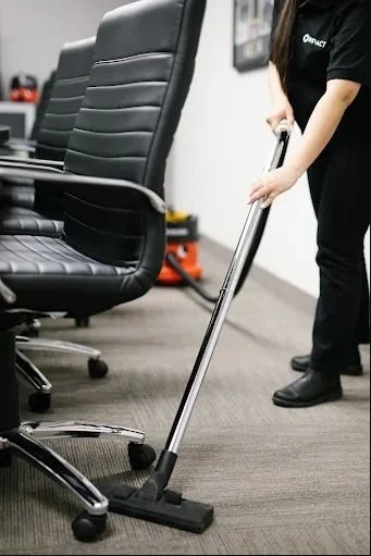 A person vacuuming office chairs in a conference room.