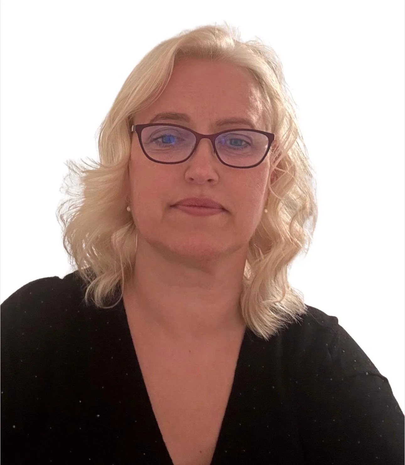 A woman with blonde curly hair wearing glasses and a black top, posing for a photo against a plain white background.