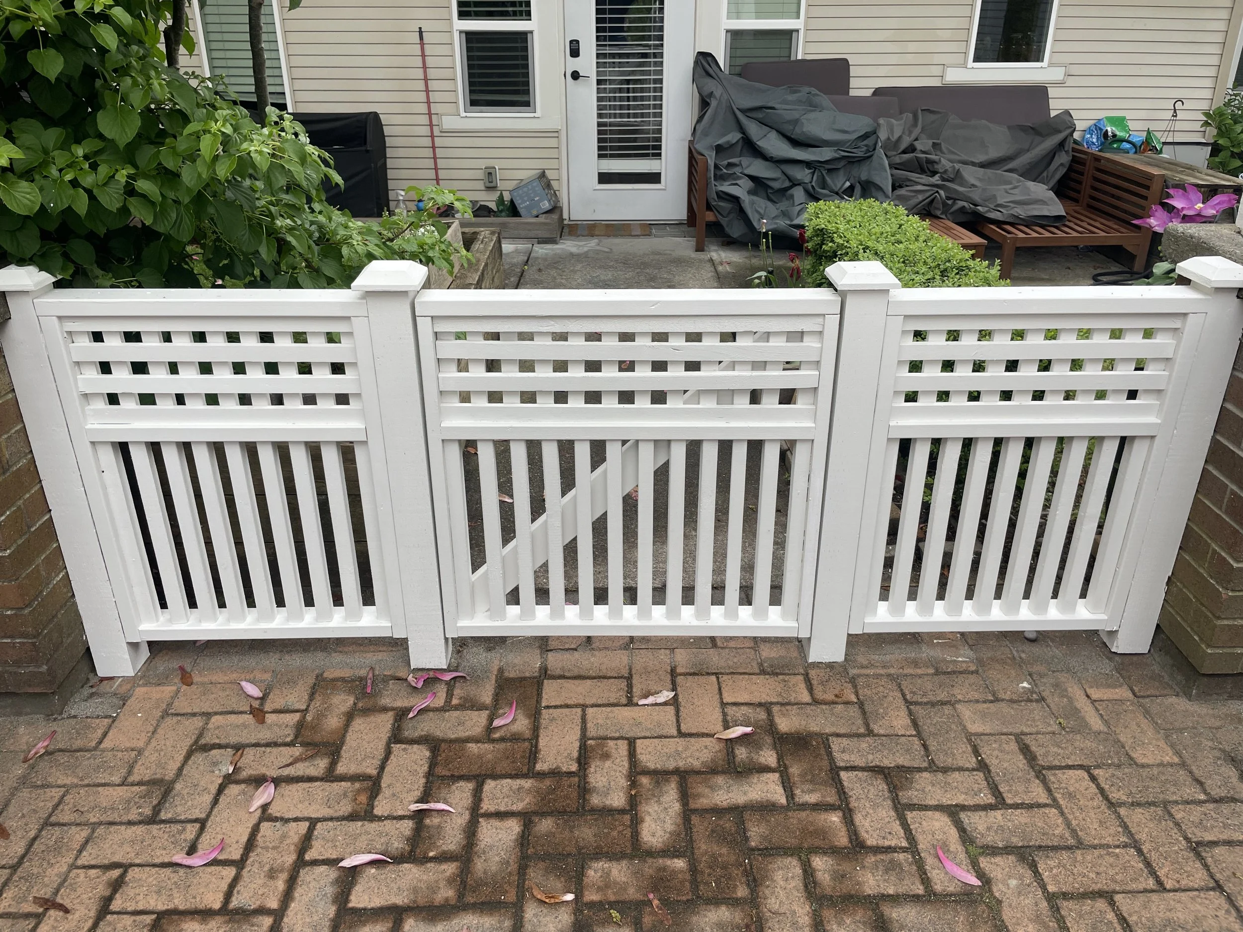 White picket fence gate with brick patio