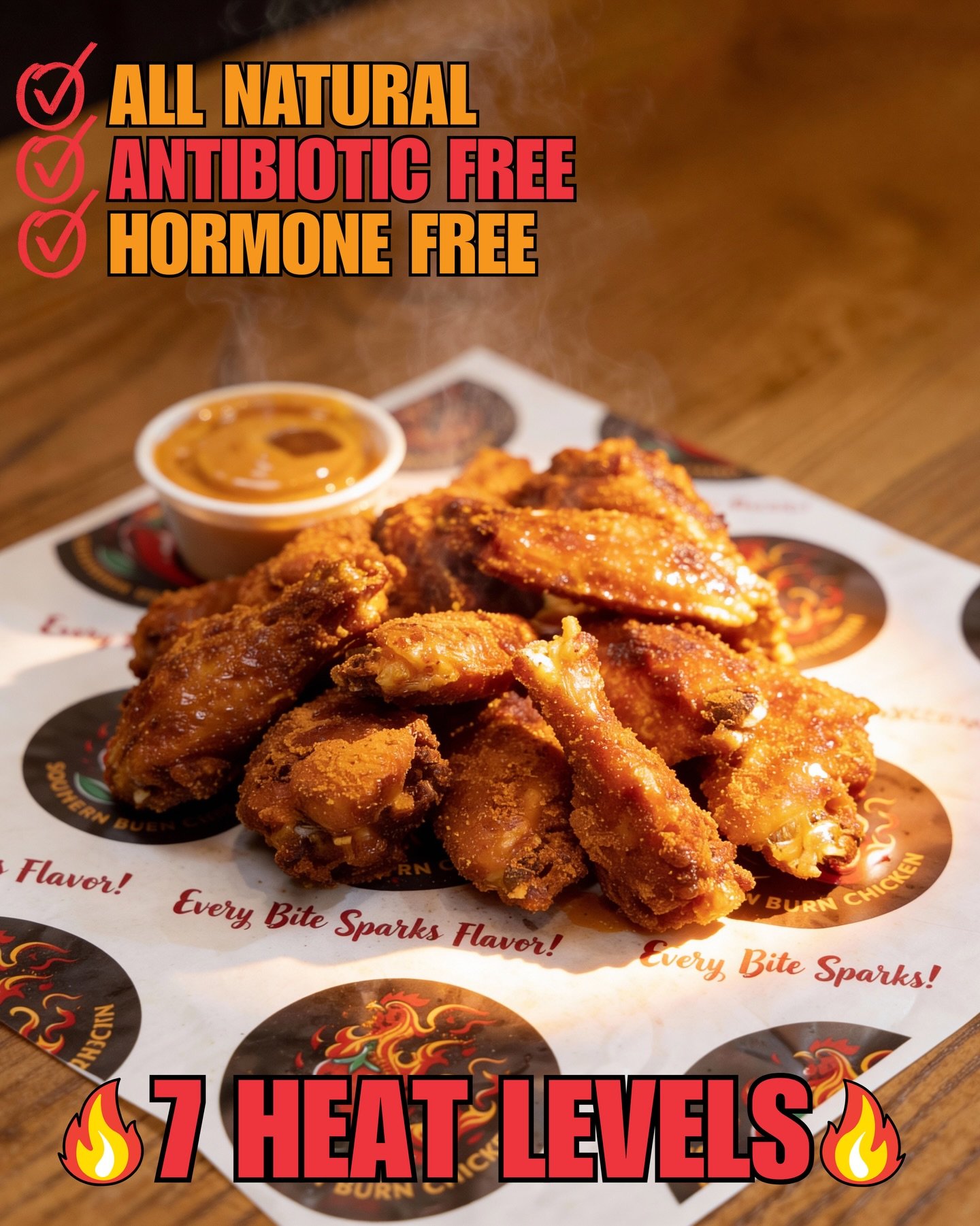 Close-up of fried chicken wings with a small cup of dipping sauce on a paper-lined plate, on a wooden table. Text overlay indicates the product is all natural, antibiotic free, hormone free, with 7 heat levels.