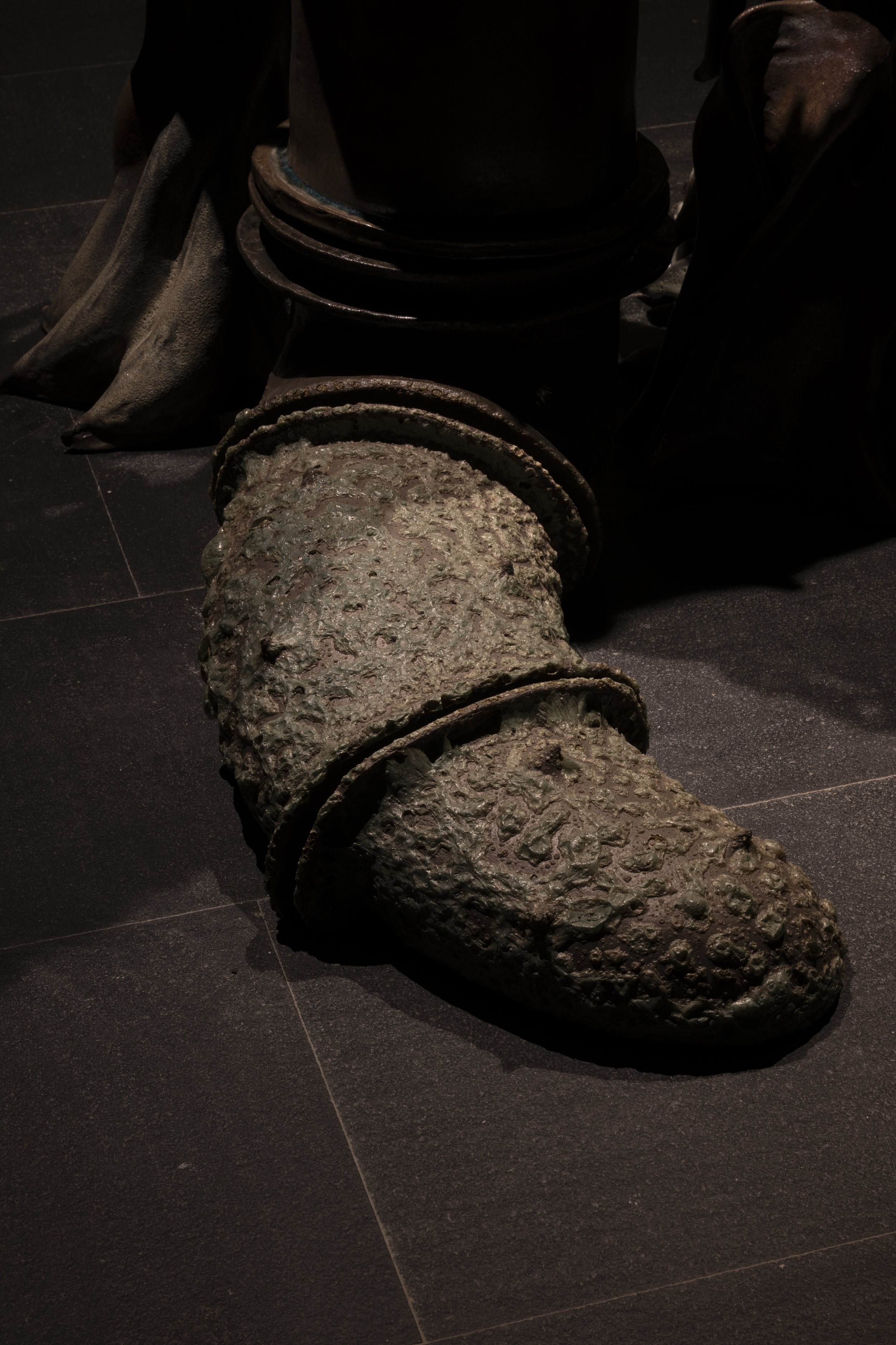 A large, corroded, and rusty cannon displayed on a dark floor.