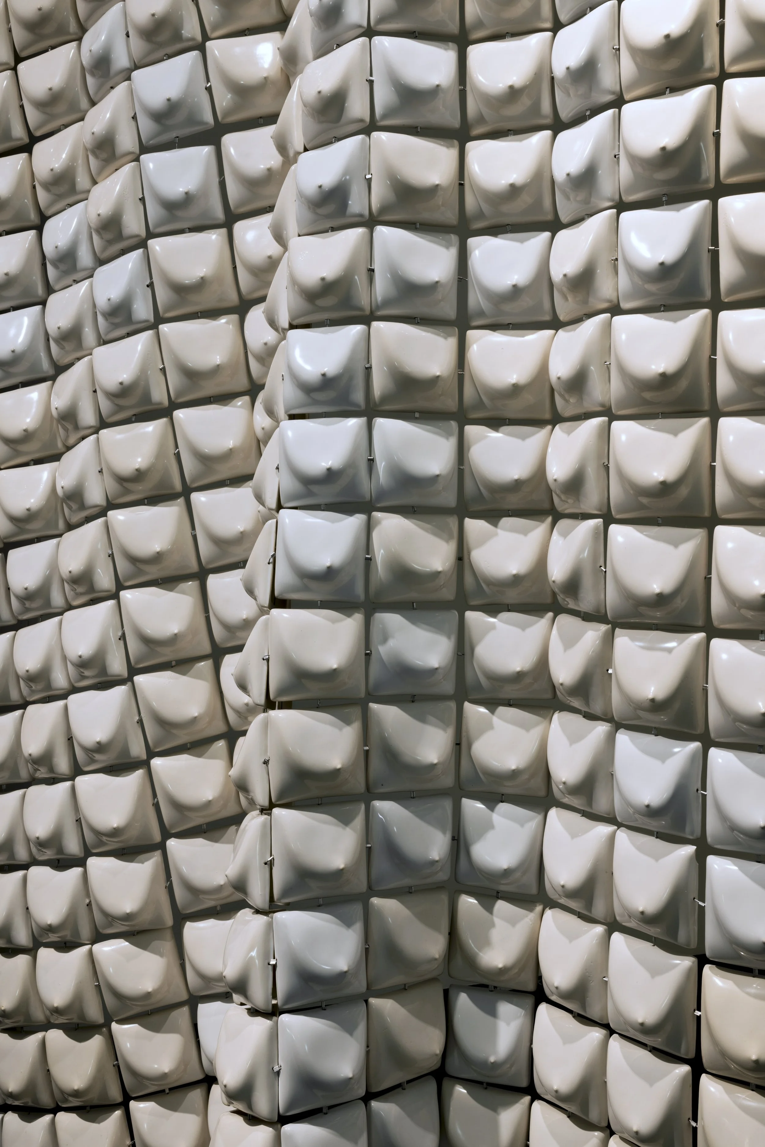 Close-up of a wall decorated with numerous white, square-shaped tiles with rounded, protruding bumps.