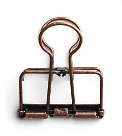 A vintage copper spring-loaded clamp against a black background.
