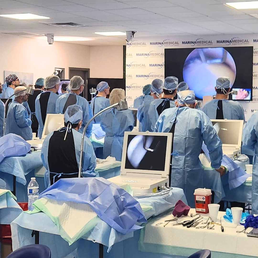Medical team in surgical scrubs and caps performing a medical procedure in an operating room.