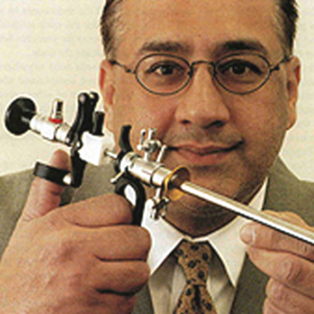 A man wearing glasses holding a vintage film camera close to his face.