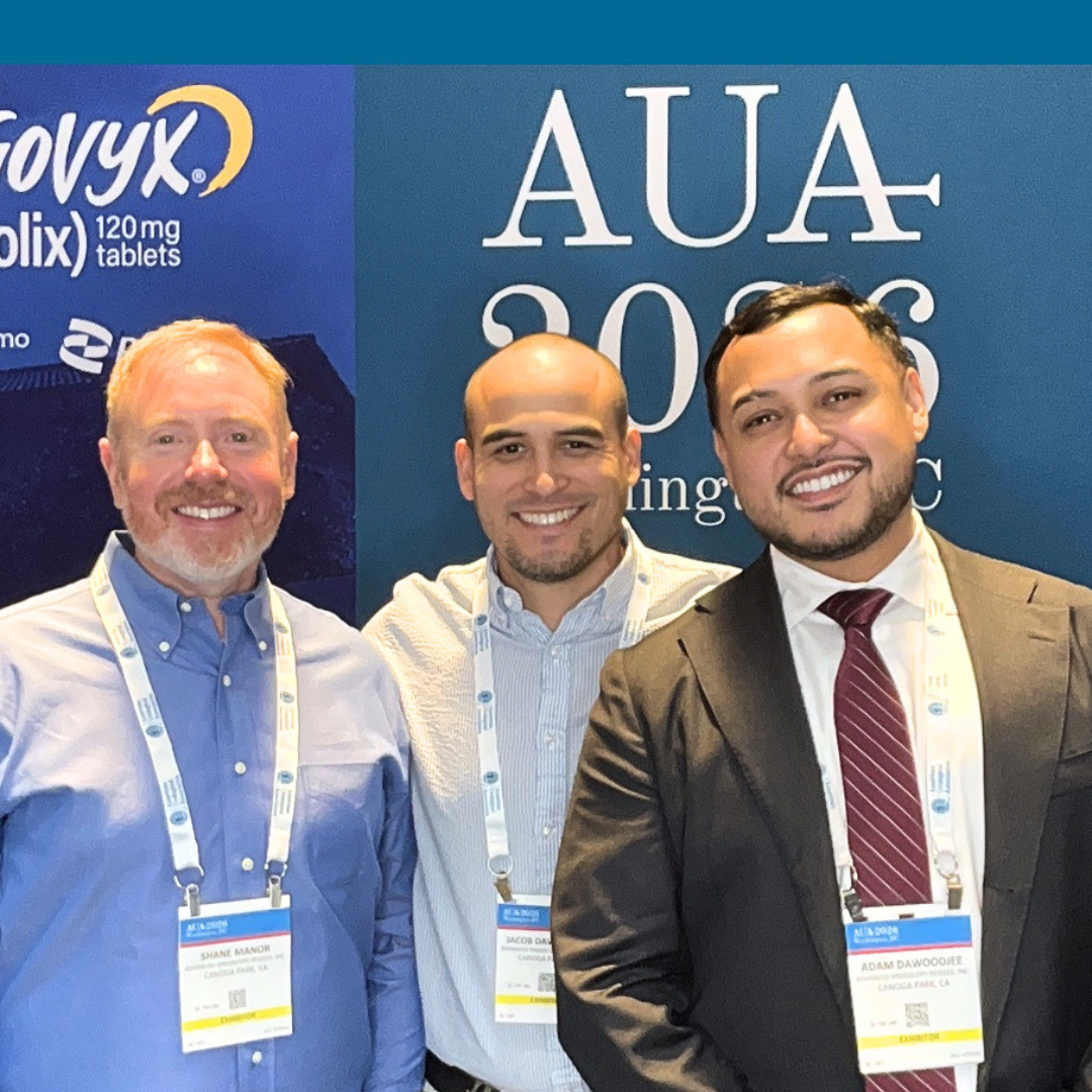 Three men standing together at a conference, smiling, with a blue banner behind them that reads "AUA 2023." The men are wearing conference badges and are dressed in business casual and professional attire.