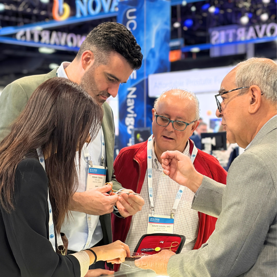 Four professionals engaged in a discussion at a conference, examining a small object or device, with conference badges visible.
