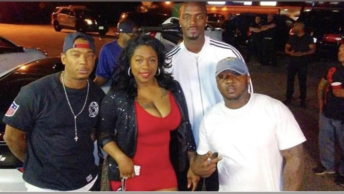 Group of five people posing together outside at night, with cars in the background. Four men and one woman, casually dressed.