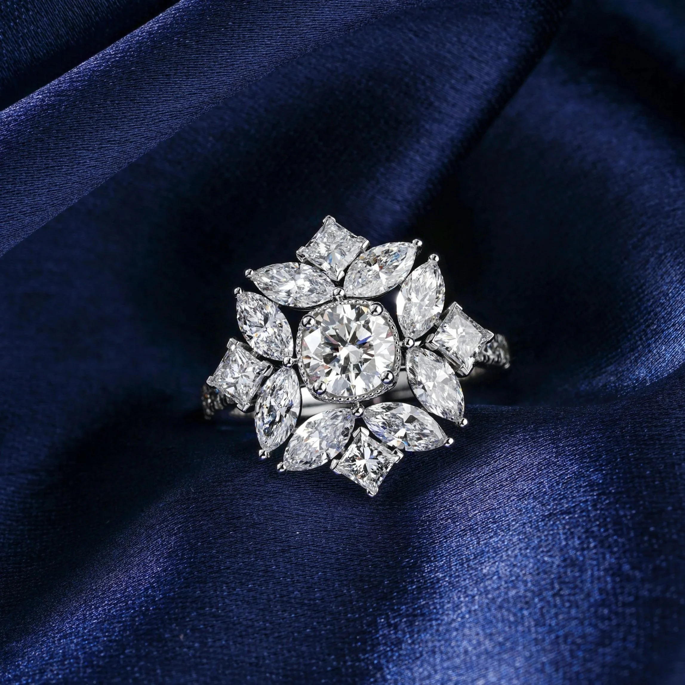 Elegant diamond ring with a floral design on dark blue satin fabric.