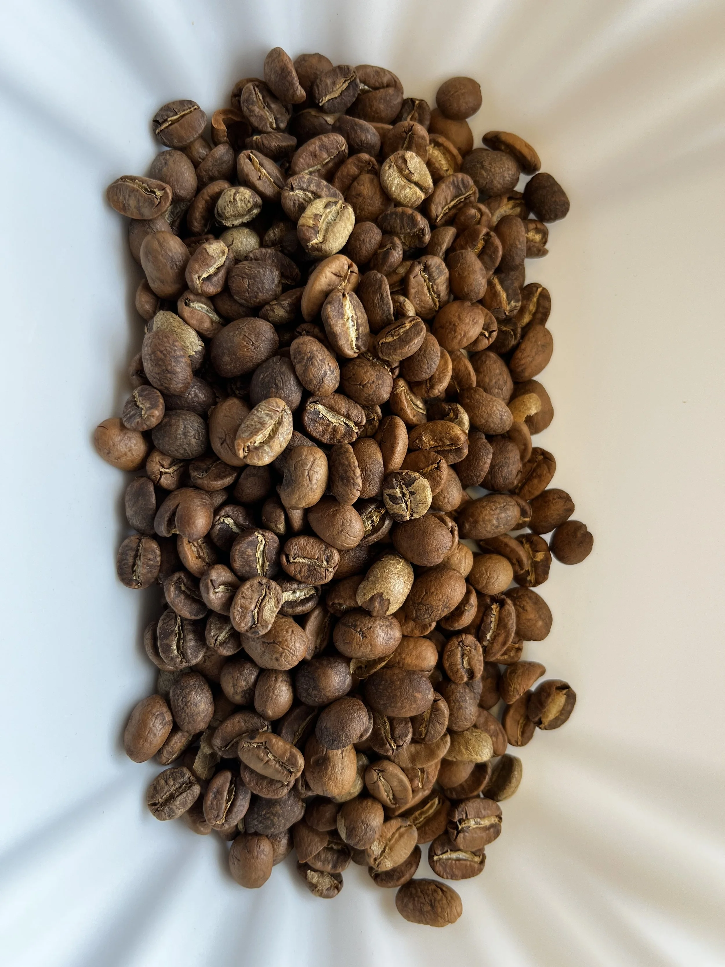 Coffee beans spread out on a white surface.