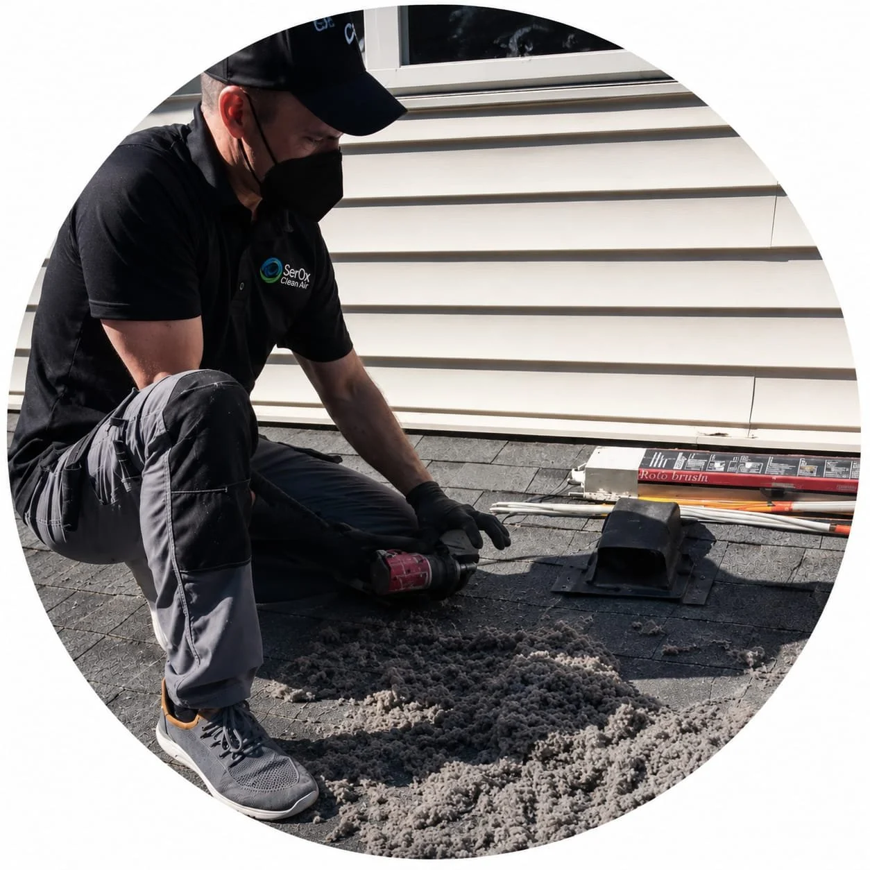 Person using a power drill with a brush attachment to clean the outside of a house's vent or exhaust pipe