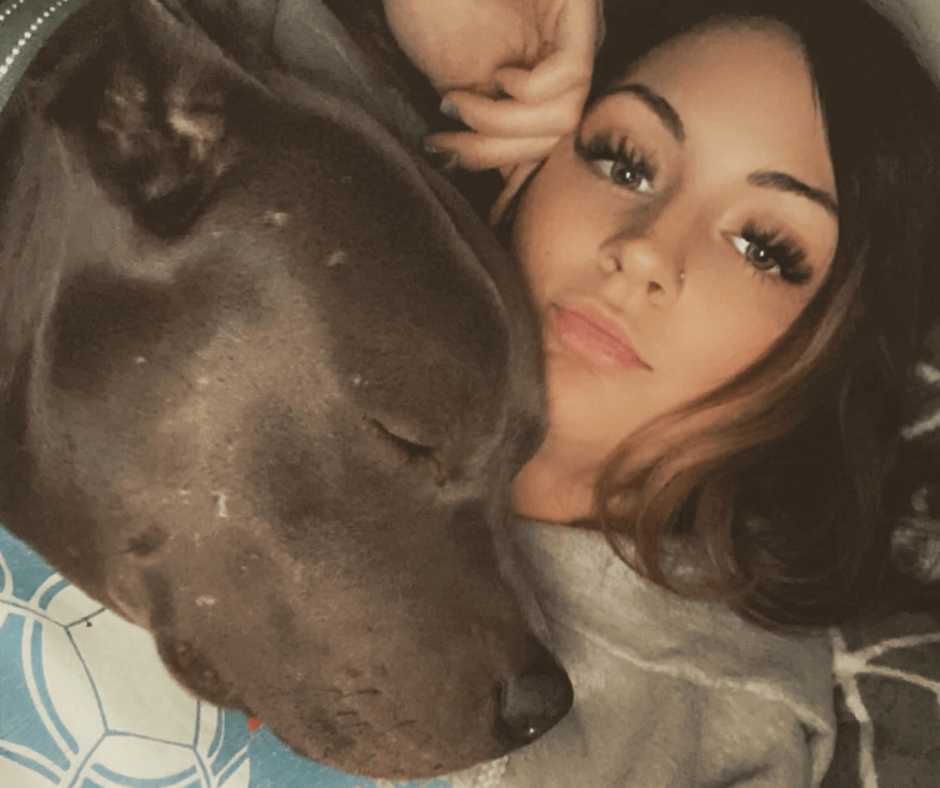 girl with brown pitbull laying on her