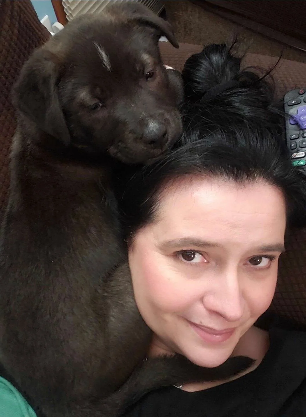 Woman smiling with black puppy wrapped around her head