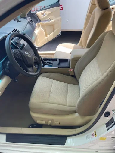 Front interior of a beige car, showing the driver and passenger seats, steering wheel, and dashboard.